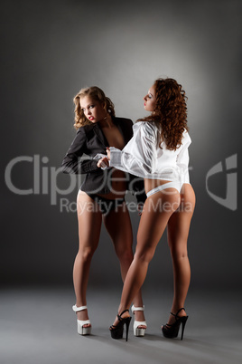 Blonde and brunette in unbuttoned shirts in studio