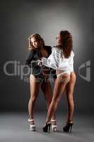 Blonde and brunette in unbuttoned shirts in studio