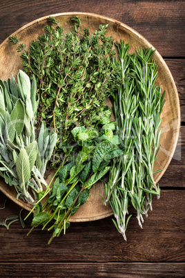 various fresh herbs, rosemary, thyme, mint and sage on wooden background