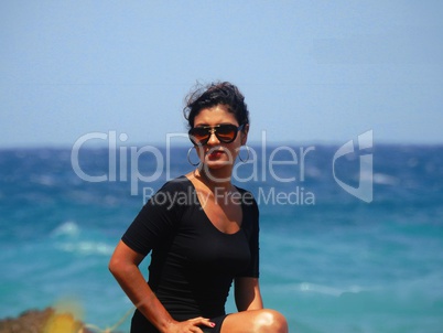 Woman Sitting By Ocean