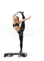 Sporty young girl streches her leg up studio shot