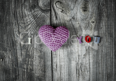 Knitted heart on gray wooden background