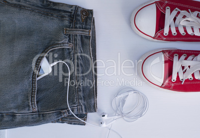 Blue jeans with mobile phone in the pocket near Youth red shoes