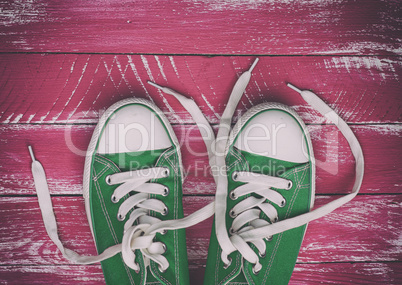 pair of worn sneakers on a pink green old wooden surface