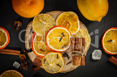 Fresh and dried oranges and lemons on a black surface