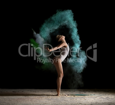 Graceful girl posing in green dust cloud in studio