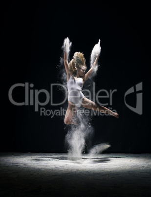 Graceful woman jumping in cloud of white dust