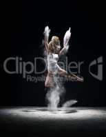Graceful woman jumping in cloud of white dust