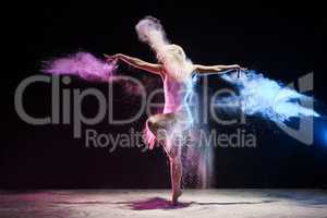 Girl in color dust cloud gracefully poses indoors