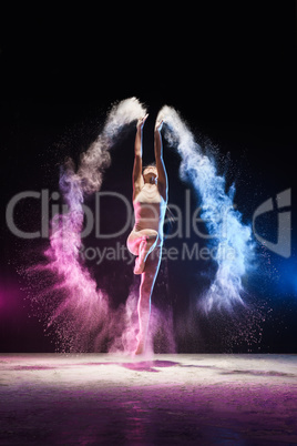 Young girl streching in jump in color dust cloud