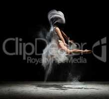 Young girl dancing in white dust color in studio