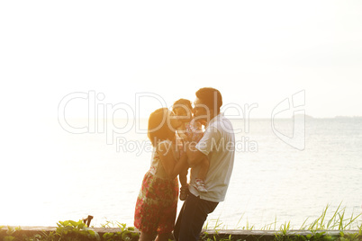 Parents kissing kid on beach sunset