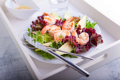 Avocado shrimp salad with mustard sauce on a tray