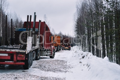 Empty long vehicles on winter road among forest