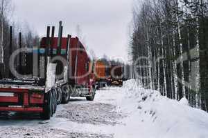 Empty long vehicles on winter road among forest