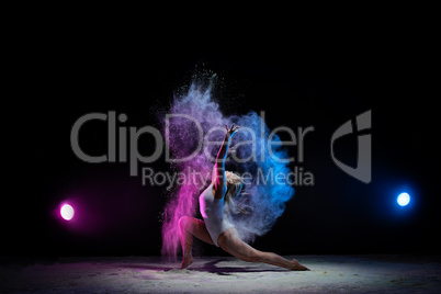 Young girl posing in color dust cloud in studio