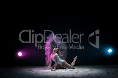 Slender girl posing in color dust cloud in studio