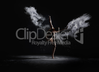 Slender girl dancing in white dust cloud