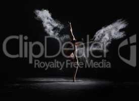 Slender girl dancing in white dust cloud