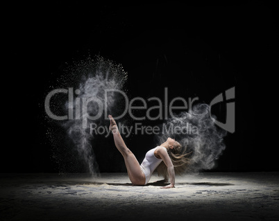 Graceful gymnast exercising in cloud of white dust