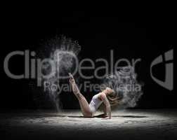 Graceful gymnast exercising in cloud of white dust