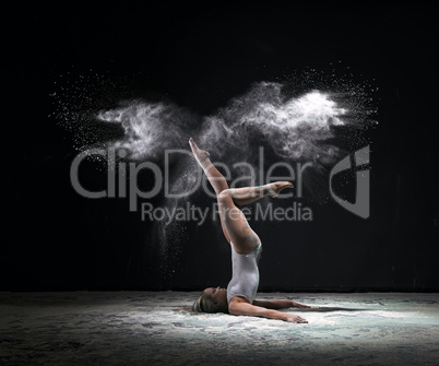 Slender woman exercising in cloud of white dust