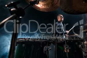 Drummer playing in smoky dark studio