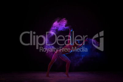 Graceful girl dancing in color powder cloud