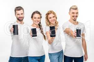 Smiling young people showing smartphones
