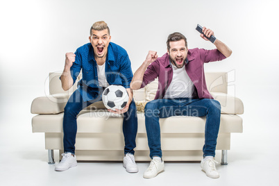 Friends sitting on couch with soccer ball