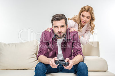 Woman looking at man playing with joystick
