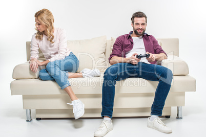 Offended woman and man playing with joystick