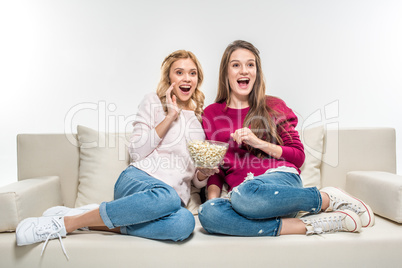 Friends eating popcorn on couch