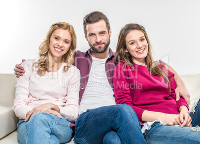 Smiling friends embracing on couch