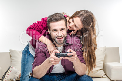 Woman hugging man playing with joystick