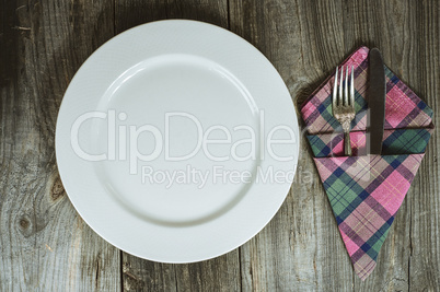 Empty plate with cutlery on a gray wooden table