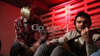 Stylish musician playing acoustic guitar in garage