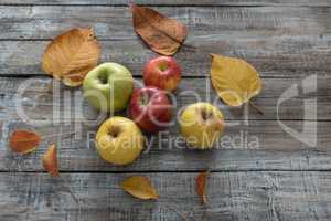 Apples and leaves on wooden boards background. Autumn concept