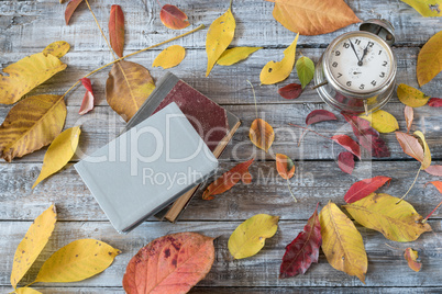 Vntage books and clock on wooden table. Autumn composition.
