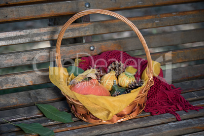 Woven basket of autumn gourds on a garden bench
