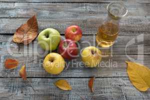 Apple cider in  bottle,  and fresh apples on wooden background