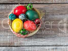 Colorful easter eggs in straw nest on a wooden table