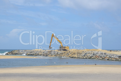 Excavator on the workplace on a background of the sea.