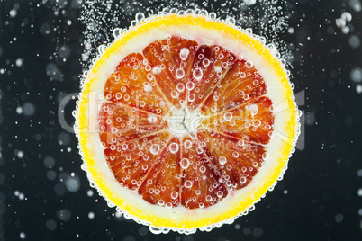 Orange citrus slice falling into water