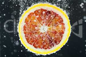 Orange citrus slice falling into water