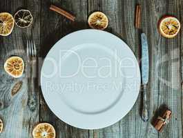 Empty white plate with cutlery, decoration dry slices of citrus