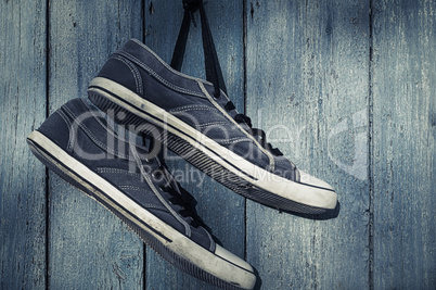 Blue textile torn sneakers hanging from a nail