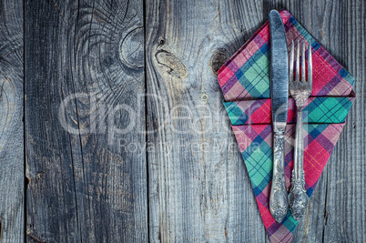 Fork and knife on a napkin, gray old wooden table