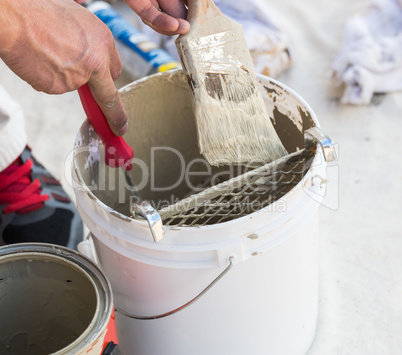 Professional Painter Loading Paint Onto Brush From Bucket