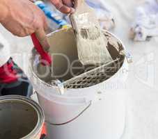Professional Painter Loading Paint Onto Brush From Bucket